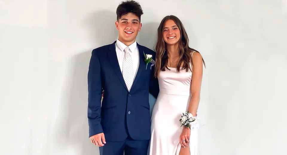 Una giovane coppia posa sorridente davanti a uno sfondo bianco nel campus del Waimea College.