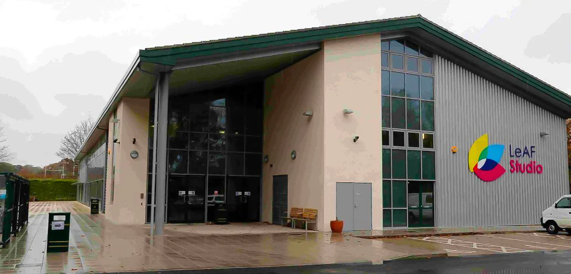 L'edificio moderno a più piani dell'Oak Leaf Studio con tetto verde e grandi vetrate è circondato da un'area pavimentata.