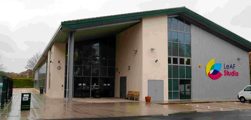 L'edificio moderno a più piani dell'Oak Leaf Studio con tetto verde e grandi vetrate è circondato da un'area pavimentata.