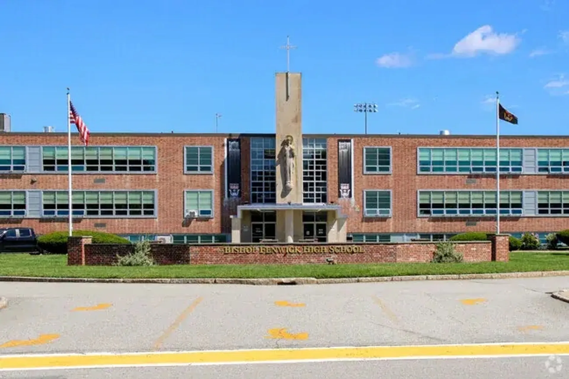 L'edificio in mattoni della Bishop Fenwick High School con una torre centrale sormontata da una croce e una statua.