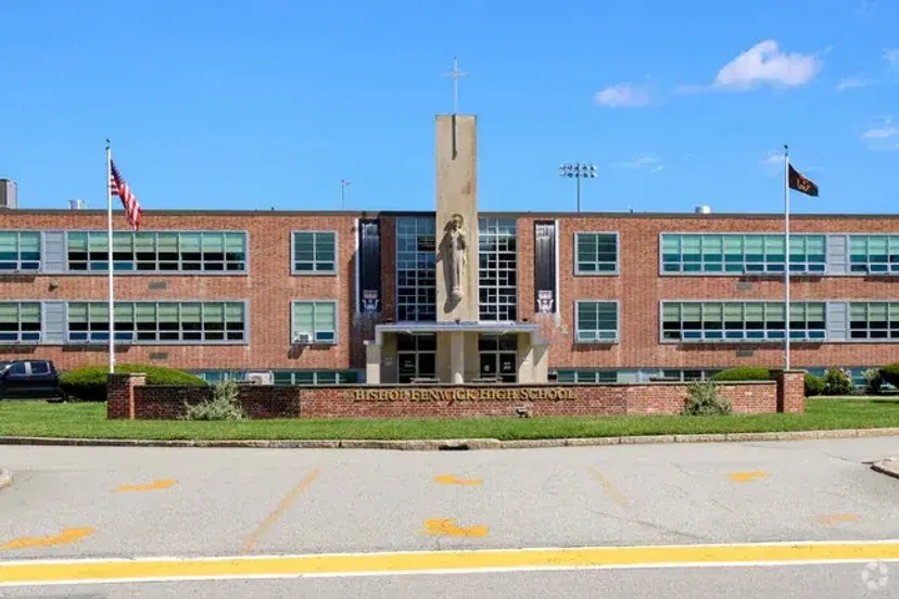 L'edificio in mattoni della Bishop Fenwick High School con una torre centrale sormontata da una croce e una statua.