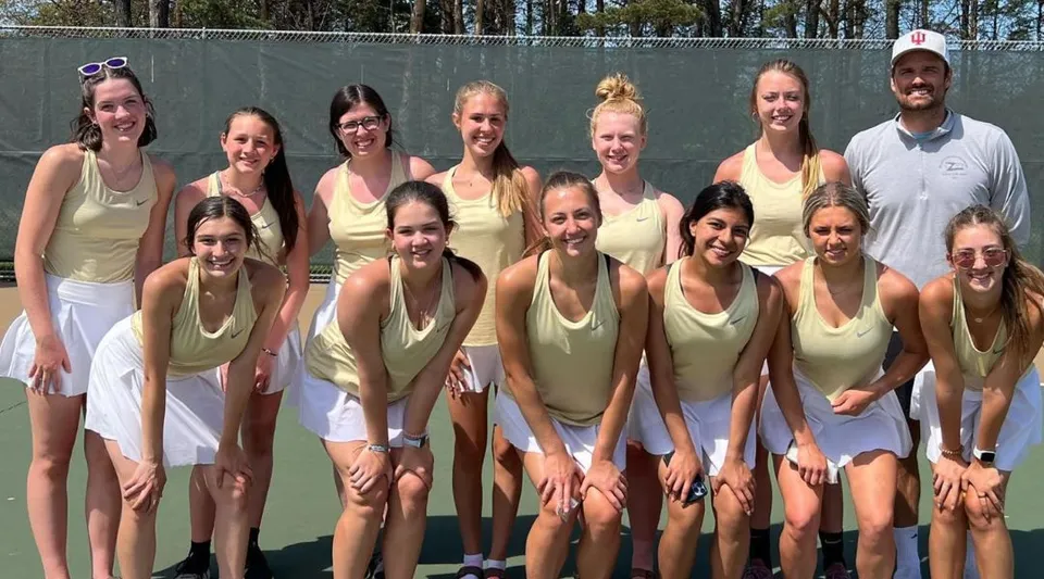 Un gruppo di studentesse della Muskegon Catholic Central High School posa sul campo da tennis davanti a uno sfondo alberato.
