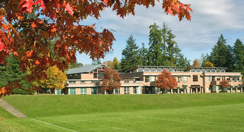 L'edificio moderno a più piani della Gulf Islands Secondary School è circondato da un prato verde e da alberi dai colori autunnali.