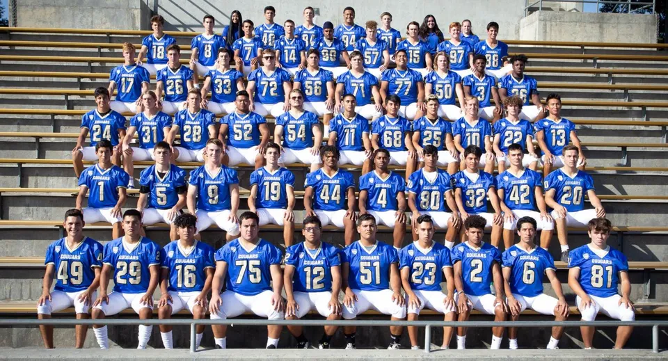 Un grande gruppo di studenti in uniforme blu sta sulle tribune dello stadio del Clovis Unified School District.