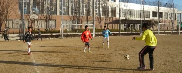 Schüler der Hinodegakuen Senior High School spielen Fußball auf dem Sportplatz vor dem Schulgebäude.