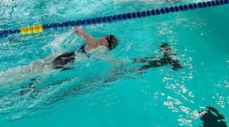 Una studentessa della Laurel School nuota nell'acqua limpida della piscina lungo la corsia.