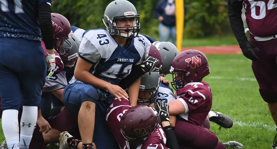 Studenti della Wallaceburg District High School giocano una partita di football americano con tackle sul campo da gioco.