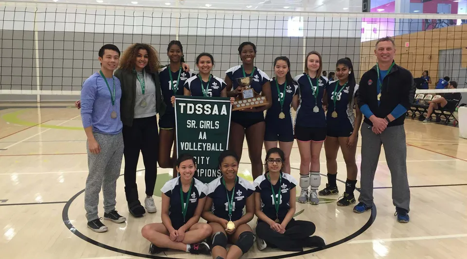 Studentesse del L'Amoreaux Collegiate Institute posano con il trofeo sul campo da pallavolo come TDSAA Sr. Girls Volleyball Champions.
