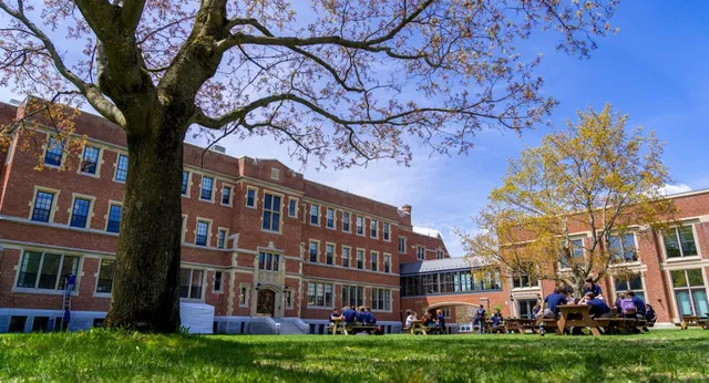 Studenti seduti a tavoli da picnic davanti agli edifici in mattoni del campus della Bishop’s College School.