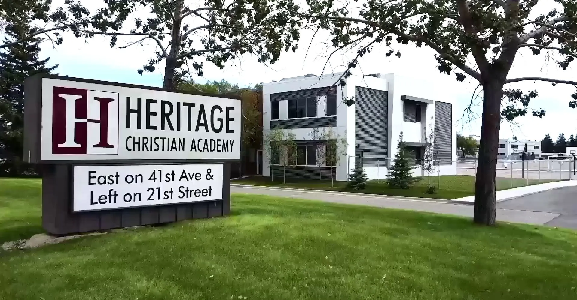 Il grande cartello della Heritage Christian Academy con l'edificio scolastico e il prato sullo sfondo.