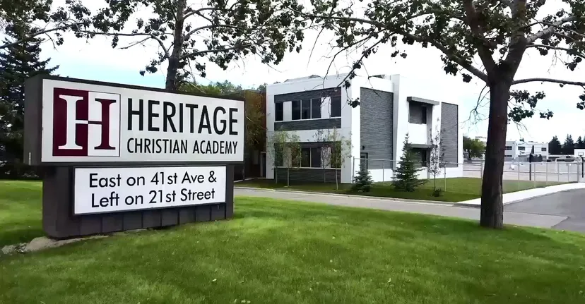 Il grande cartello della Heritage Christian Academy con l'edificio scolastico e il prato sullo sfondo.