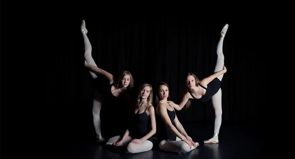 Quattro ballerine eseguono una coreografia acrobatica sincronizzata sul palco della Ernest Manning High School.
