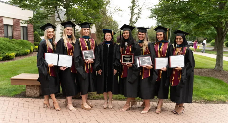 Un gruppo di diplomate e diplomati del Dominican College Galway si trova all'aperto su un sentiero lastricato circondato da una verde vegetazione.