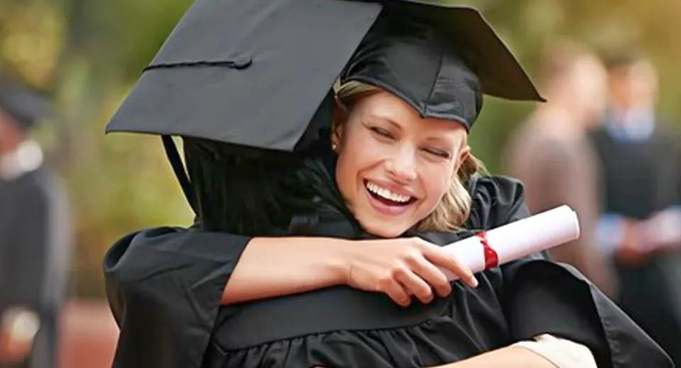 Una diplomata della Rochedale State High School sta sorridente all'aperto nel terreno della scuola con il diploma.