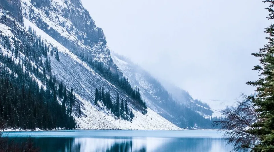 Un lago tranquillo con acqua turchese e montagne innevate sullo sfondo nei pressi della Bawlf School.