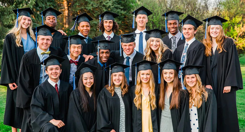 Un gruppo di diplomati della Robert Thirsk High School è insieme all'aperto in abito accademico.