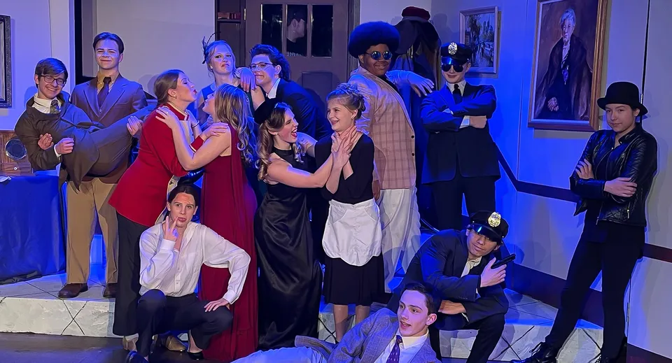 Un gruppo di persone in abbigliamento formale e casual all'interno del campus della Martin Luther High School davanti ad opere d'arte e ritratti.