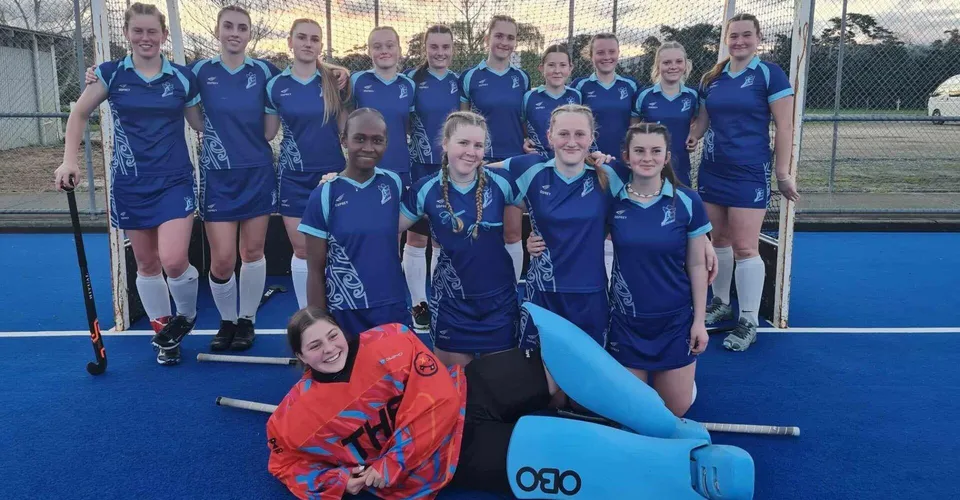Un gruppo di giovani atlete in divisa blu posa sul campo sportivo della Trident High School davanti a un grande oggetto gonfiabile.
