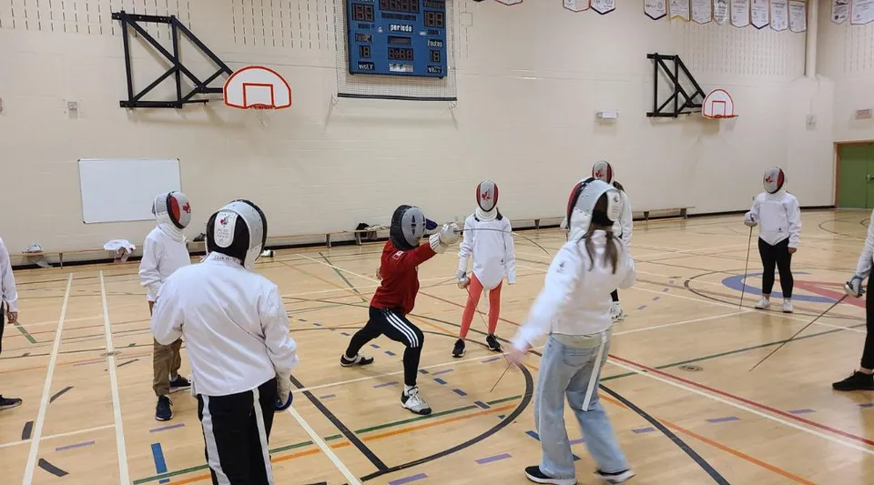 Un gruppo di studenti nella palestra con canestri da basket nel campus della Carrefour de l’Acadie.