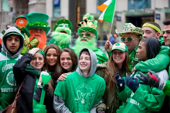 Grupo de personas sonrientes vestidas de verde con sombreros y gorros en la calle