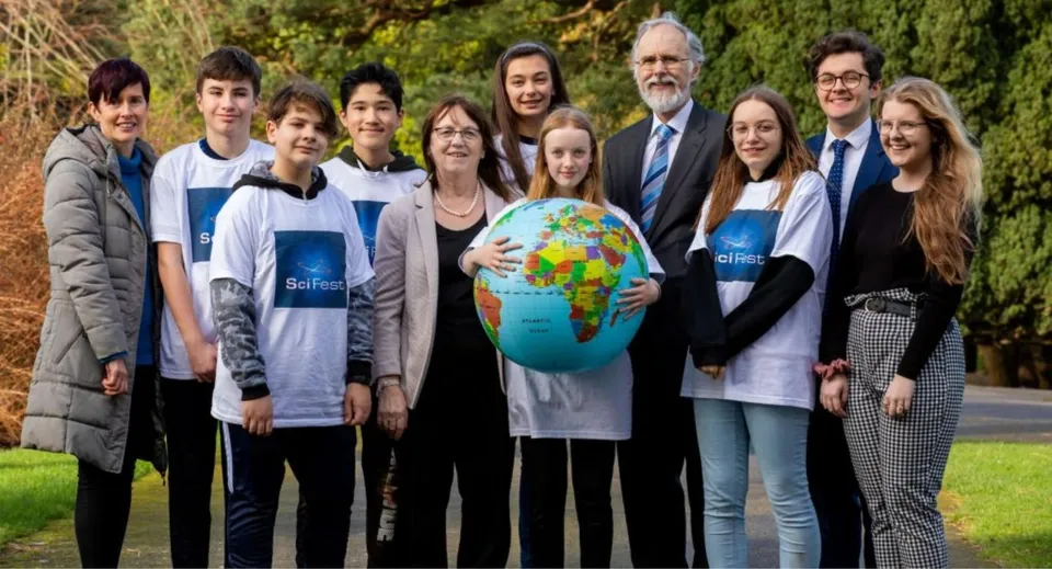 Studenti e adulti della North Wicklow Educate Together Secondary School tengono insieme un mappamondo all'aperto.