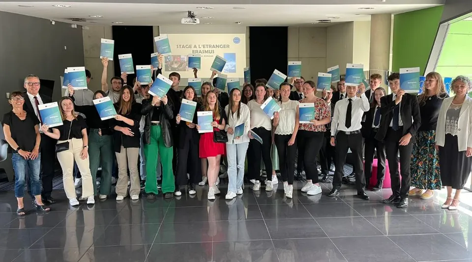 Un gruppo di giovani sta insieme in una stanza con una parete verde nel campus del Lycée Immaculée Jean Paul II.