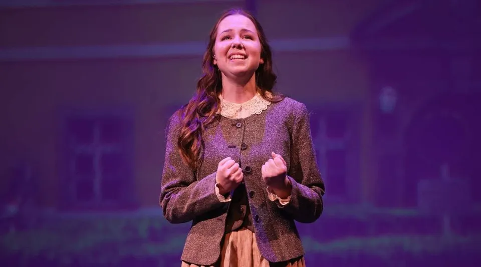 Una studentessa della Valley Christian High School sta sul palco davanti a uno sfondo viola.