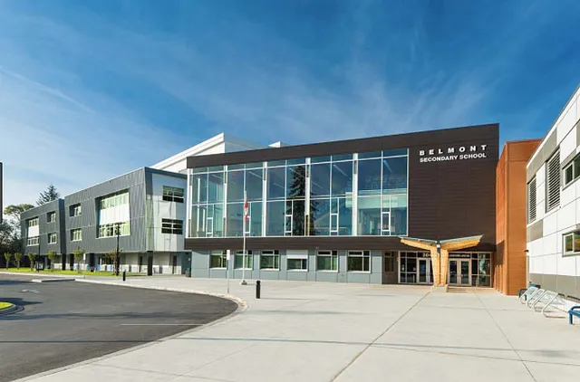L'edificio moderno a più piani con facciata in vetro della Belmont Secondary School è circondato da un'area pavimentata e zone verdi.