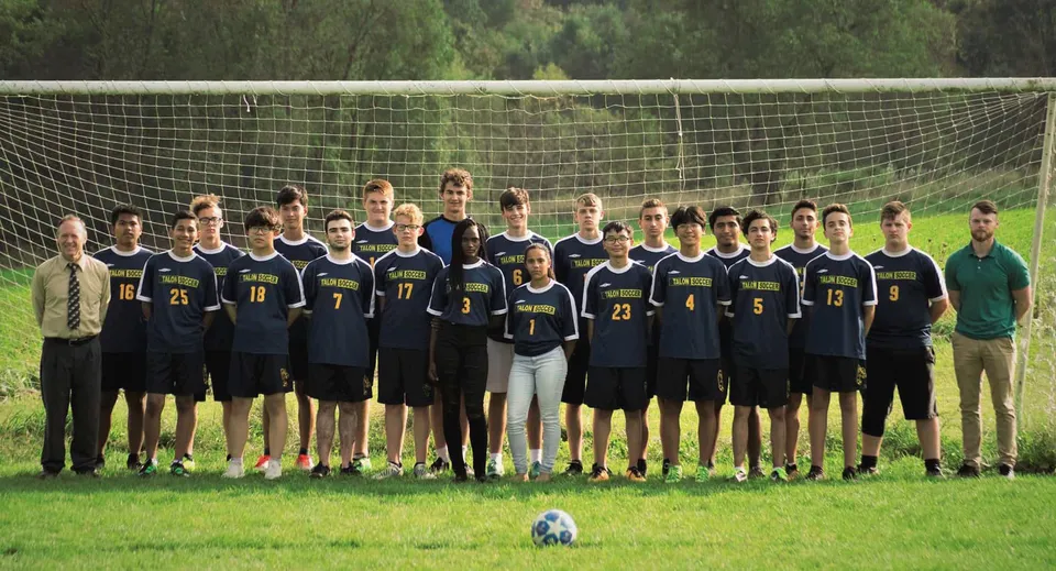 Un gruppo di studenti della Eagle School si trova insieme su un campo in erba come squadra di calcio.