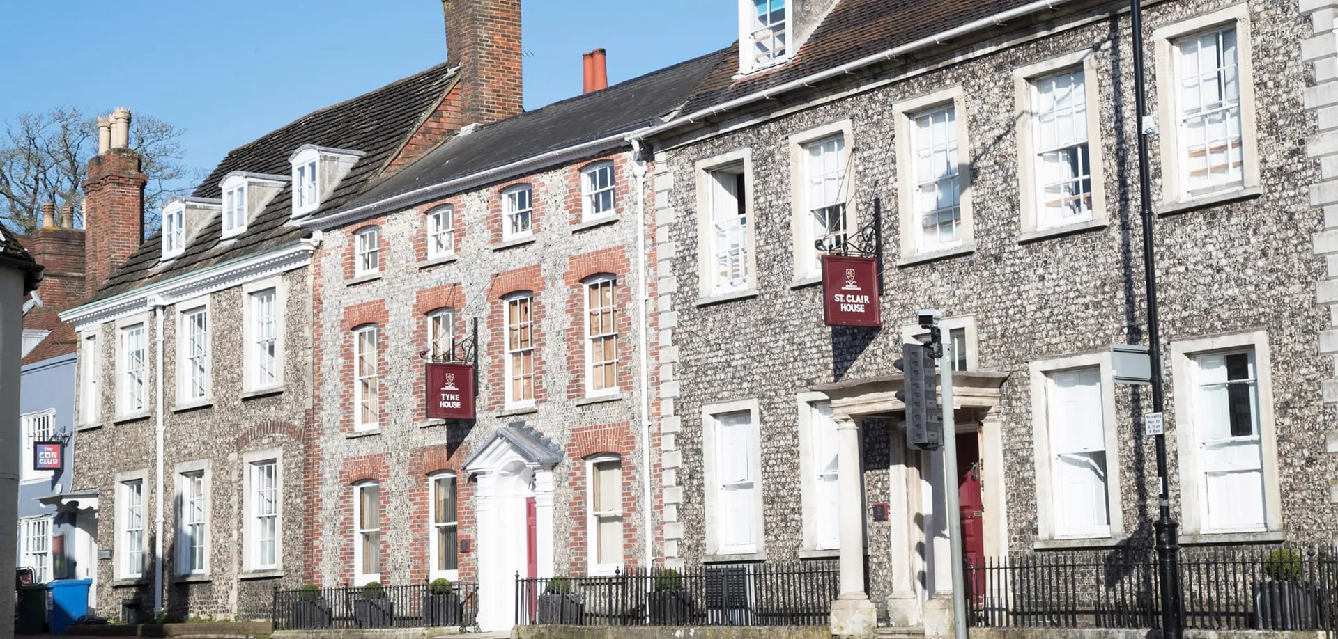 Una serie di antichi edifici in mattoni con un'architettura elaborata all'interno del campus della Lewes Old Grammar School sotto un cielo azzurro e limpido.