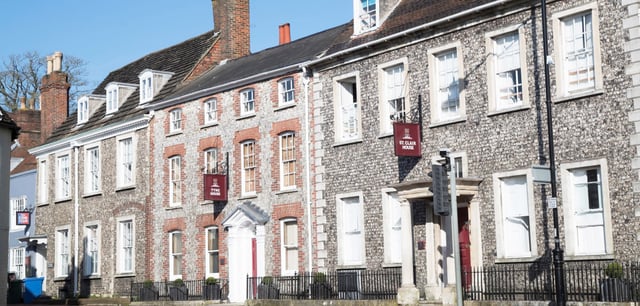 Una serie di antichi edifici in mattoni con un'architettura elaborata all'interno del campus della Lewes Old Grammar School sotto un cielo azzurro e limpido.