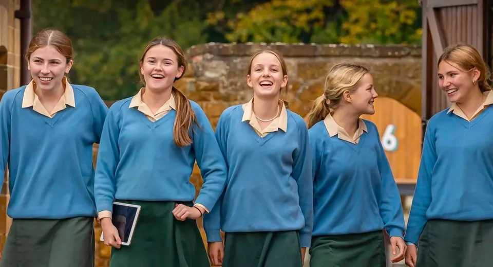Un gruppo di cinque studentesse della Tudor Hall School chiacchiera in autunno davanti al fogliame autunnale.