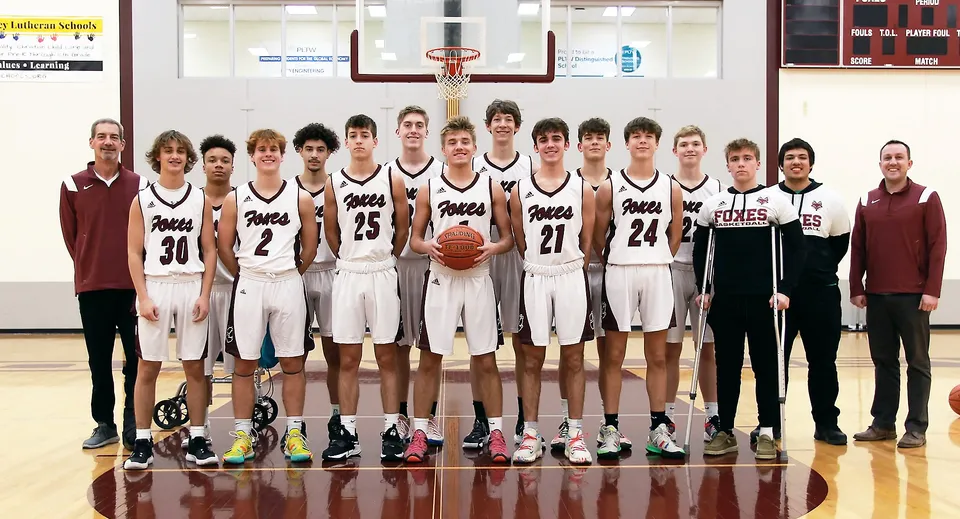 Un gruppo di studentesse e studenti della Fox Valley Lutheran High School posa insieme in palestra davanti a un canestro da basket.