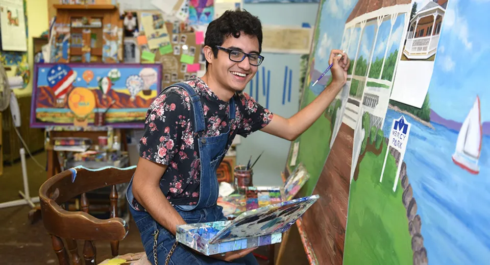 Uno studente del Clark County School District dipinge su una tela con pennello e tavolozza nell'aula d'arte.