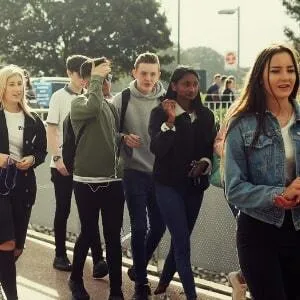 Jugendliche in Alltagskleidung gehen gemeinsam einen Gehweg entlang
