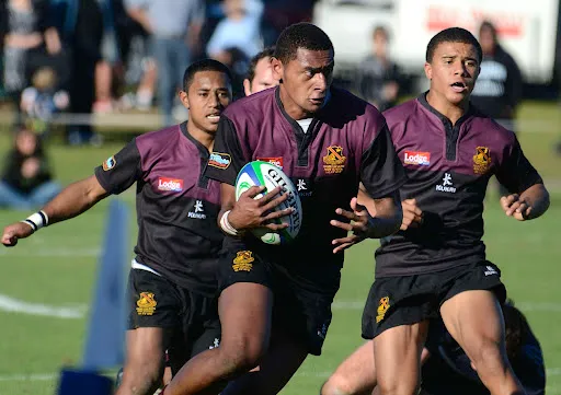 Un grupo de jugadores de rugby lleva sus camisetas granates durante el partido en el campo de la Hamilton Boy's High School.