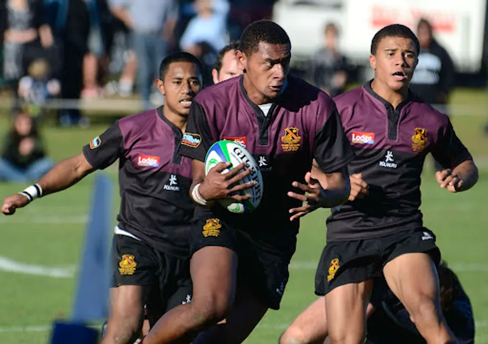 Un gruppo di giocatori di rugby indossa la propria maglia color granata durante la partita sul campo della Hamilton Boy's High School.
