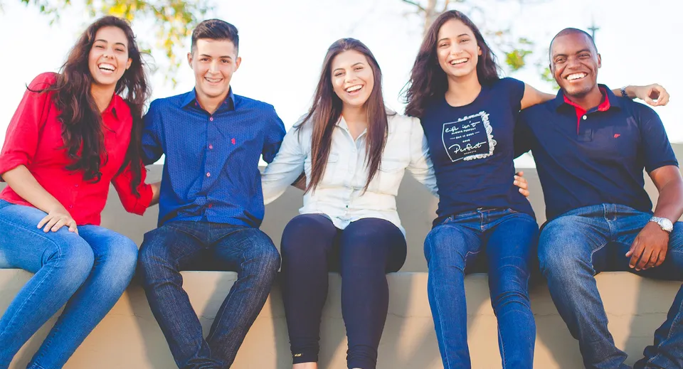 Un gruppo di cinque studenti e studentesse siede ridendo all'aperto nel campus del South Hill Education Centre.