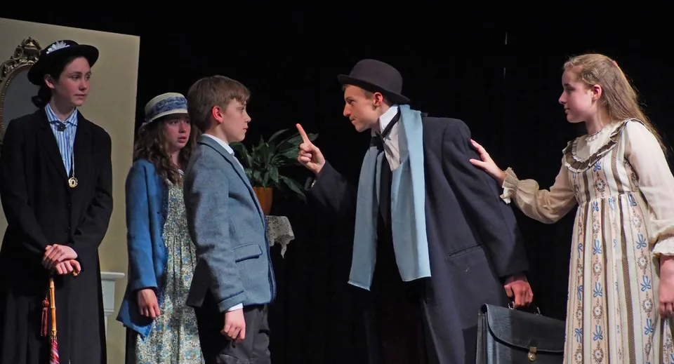 Studenti della Leweston School mettono in scena uno spettacolo teatrale in costumi d'epoca su un palco buio.