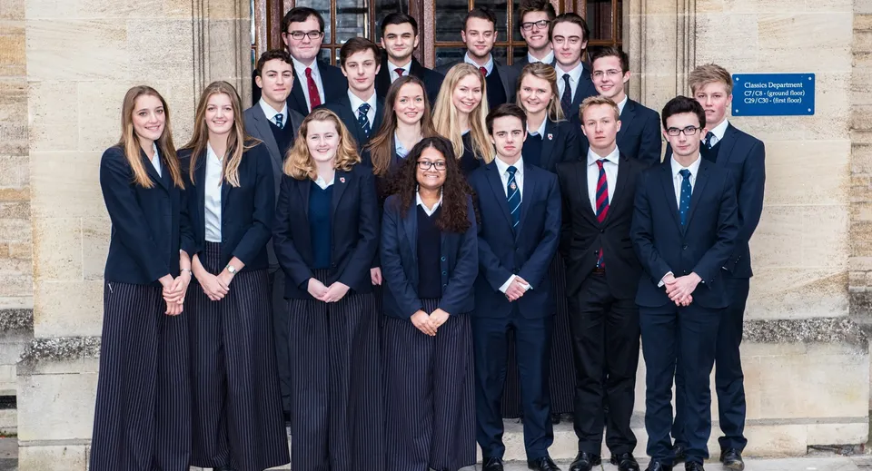 Un gruppo di studenti della Oundle School in abito formale davanti a un edificio della scuola.
