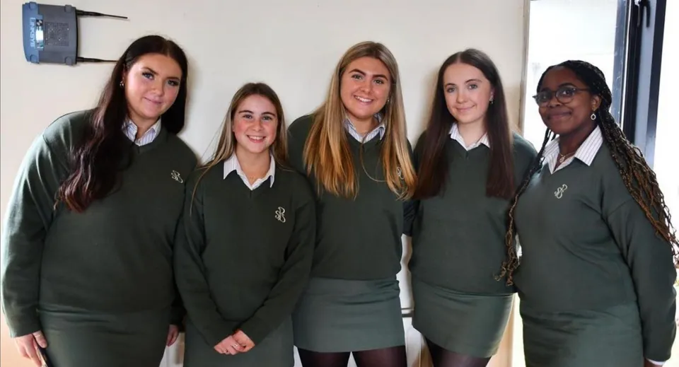 Un gruppo di cinque studentesse in divisa scolastica verde si trova insieme nel campus della Presentation Secondary School a Cork.