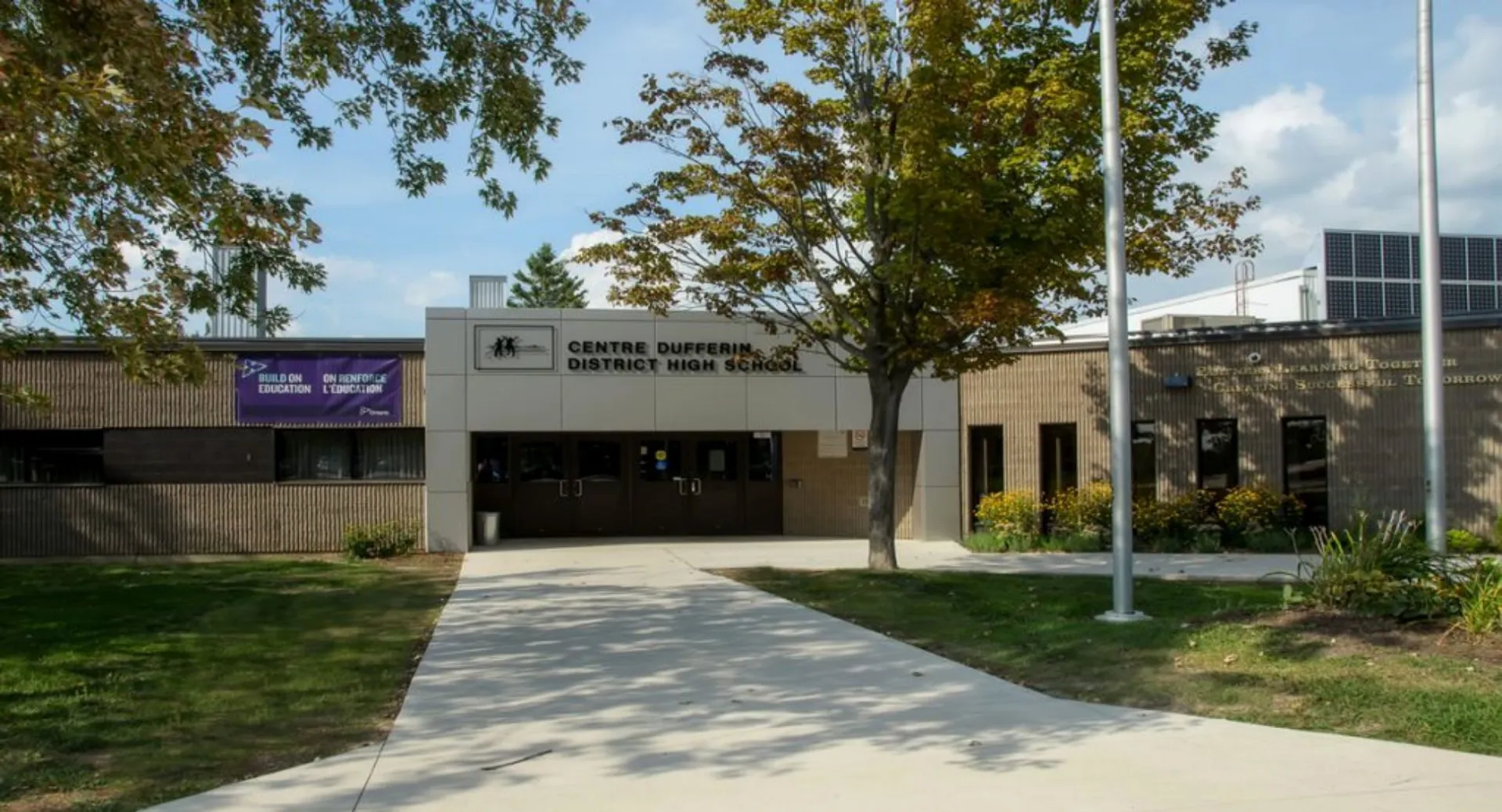 L'edificio moderno a due piani con un viale verso l'ingresso nel campus della Centre Dufferin District High School è circondato da alberi.