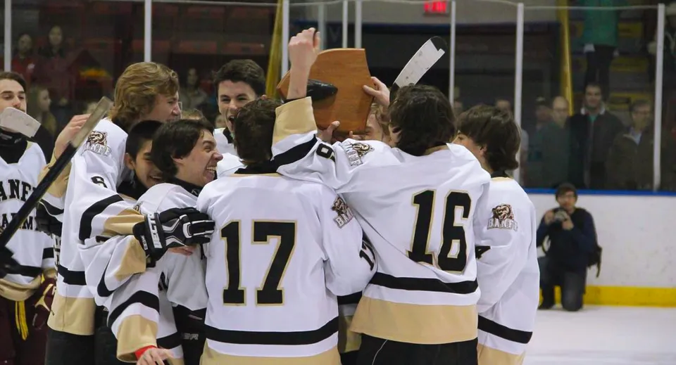 I giocatori di hockey della Banff Community High School festeggiano insieme sul ghiaccio davanti al pubblico.