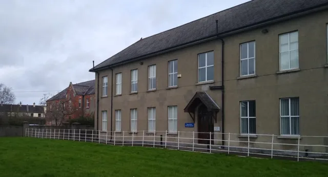 L'edificio in mattoni a più piani della Kilkenny City Vocational School con tetto a spiovente si trova davanti a un cielo nuvoloso.