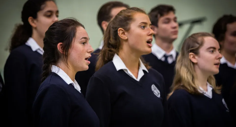 Un gruppo di studenti del St. Andrew's College canta insieme in aula.