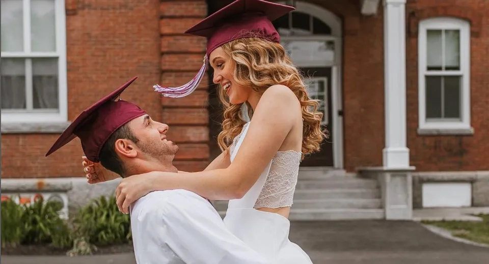 Una giovane coppia in toga si abbraccia davanti a un edificio in mattoni nel campus del Maine Central Institute.