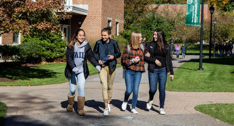 Quattro studenti camminano insieme su un viale lastricato nel campus della New Hampton School.