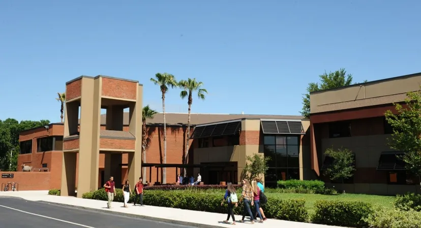 L'edificio moderno in mattoni della Orangewood Christian School con palme e persone in primo piano.