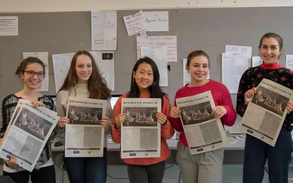 Cinque studentesse della Cambridge Rindge and Latin High School sono in un'aula con dei giornali.