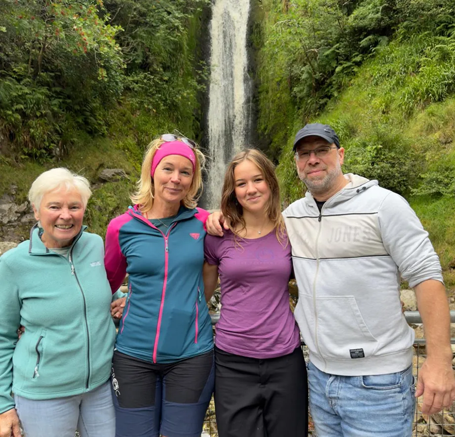 Familia posando ante una cascada rodeada de vegetación